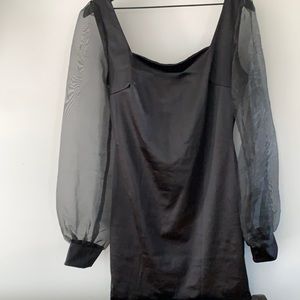Sateen black cocktail dress with sheer sleeves. Above the knee.